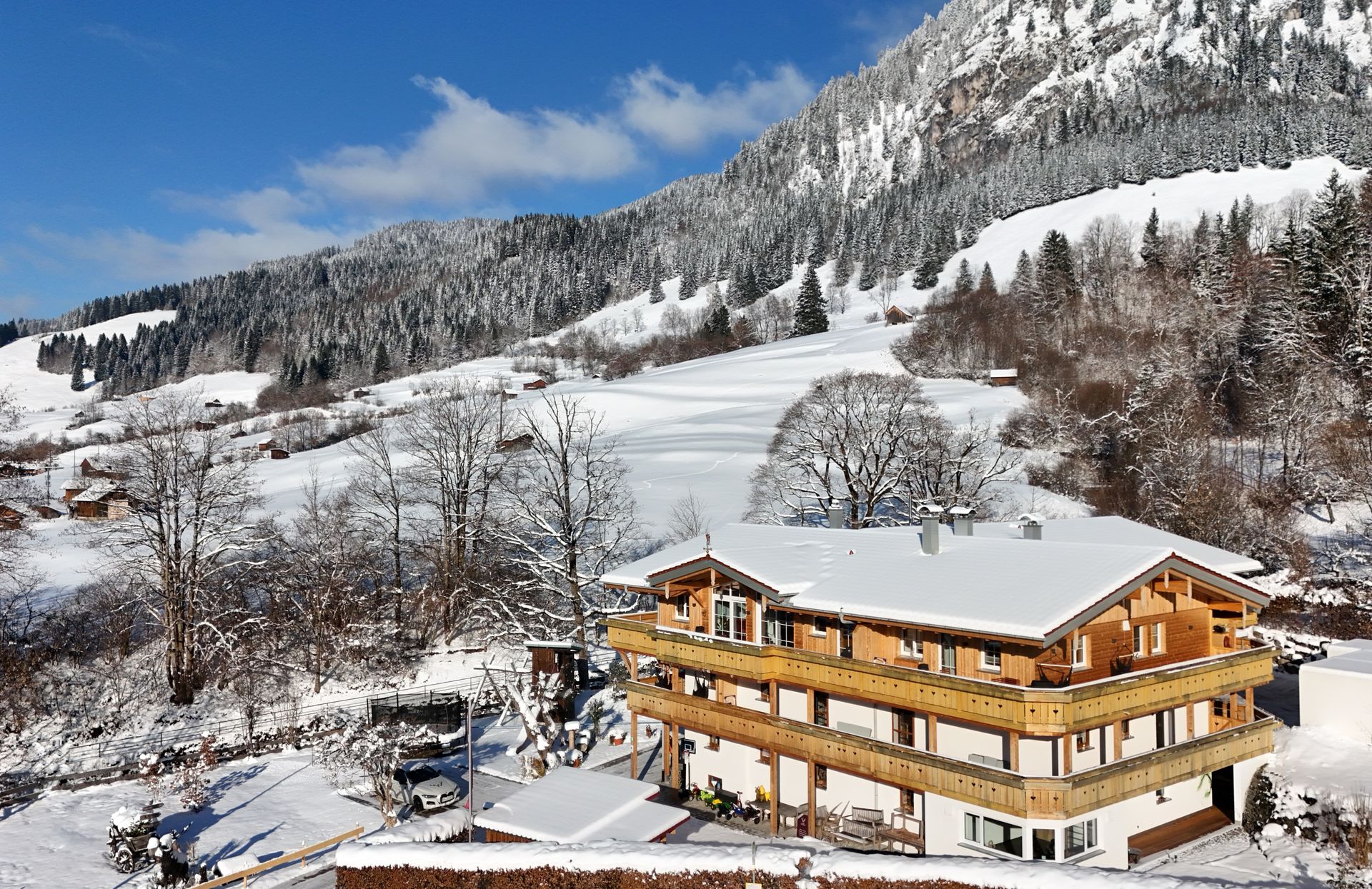 Ein großes Holzhaus ist von Bäumen und Bergen umgeben.