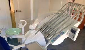 Una silla dental en un consultorio dental con una silla azul.