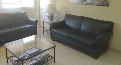 Una sala de estar con dos sofás de cuero negro y una mesa de café de cristal.