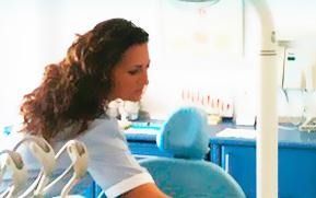 Una mujer está sentada en una silla dental en un consultorio dental.