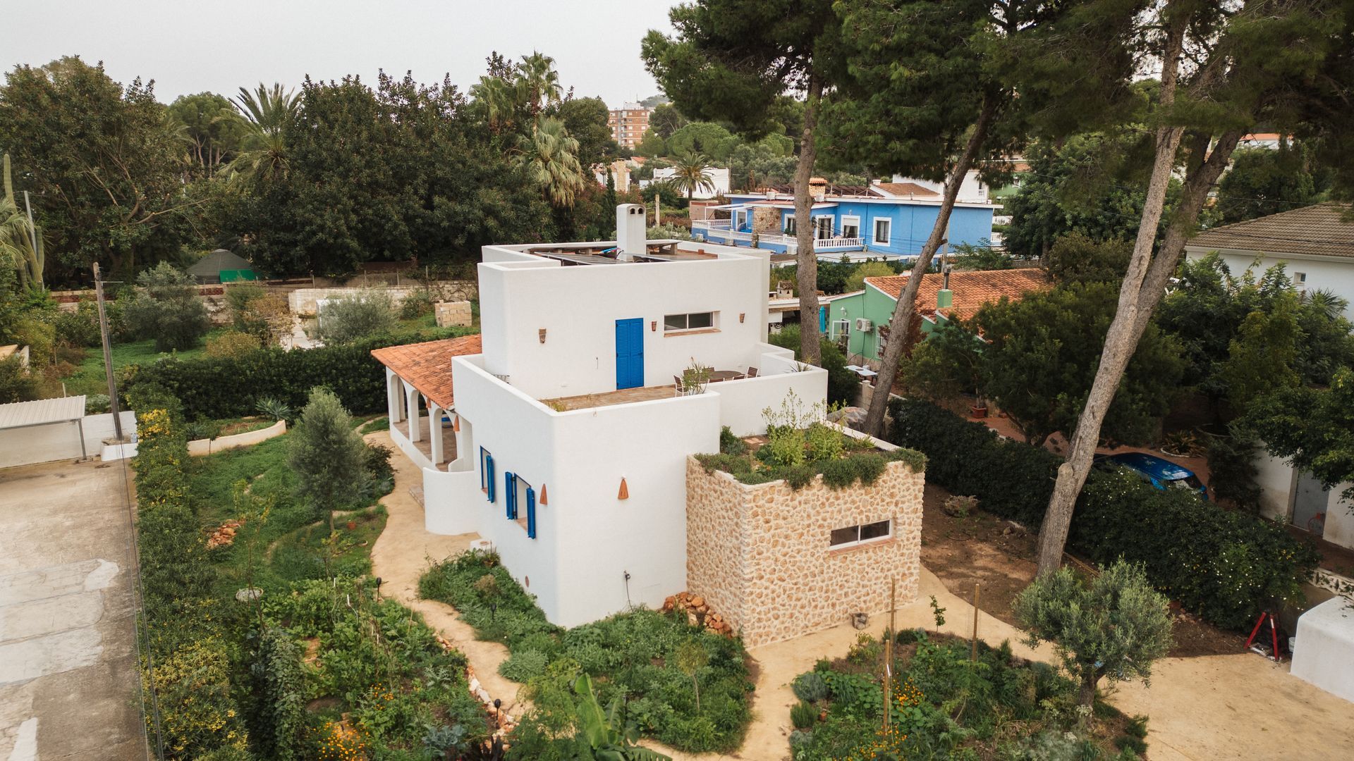 Un edificio blanco con forma de hongo con una puerta de madera en medio de un bosque.