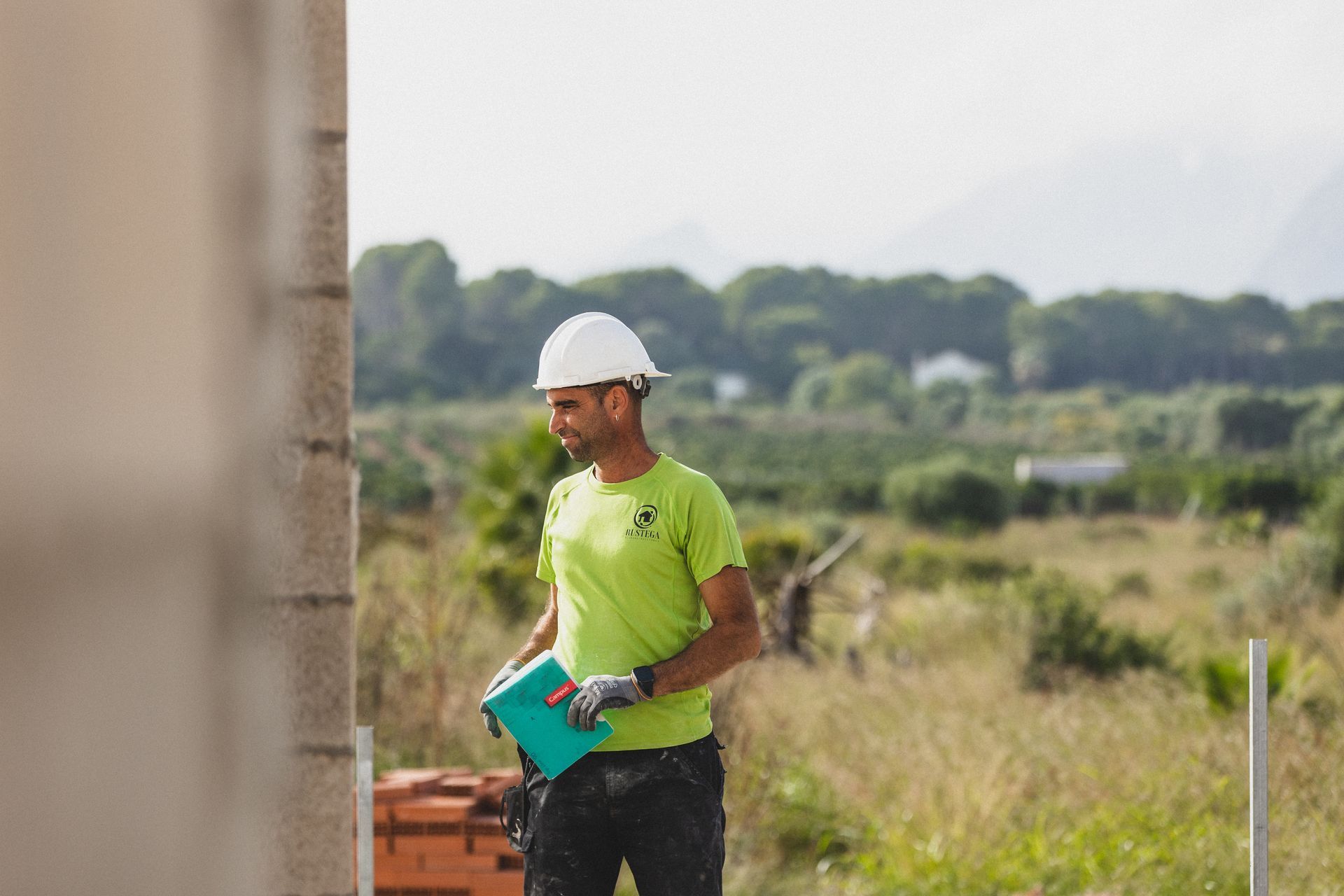 Un hombre con una camisa verde está trabajando en una pared.