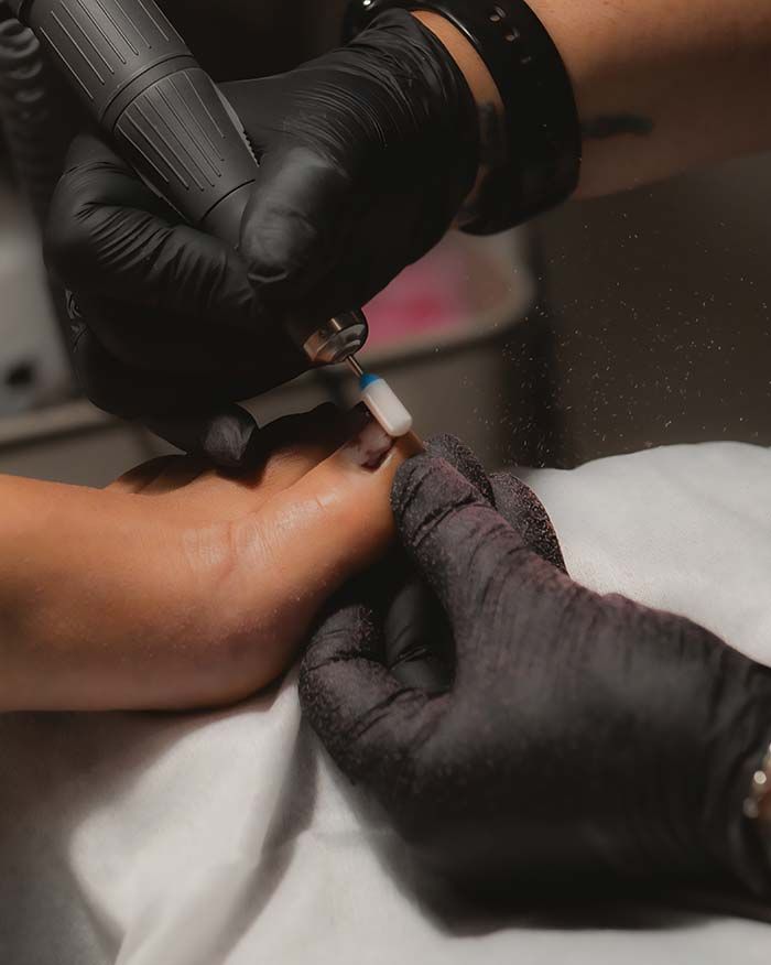 Dedos de una persona recibiendo un tratamiento de manicura, limados por un profesional en un salón de uñas.