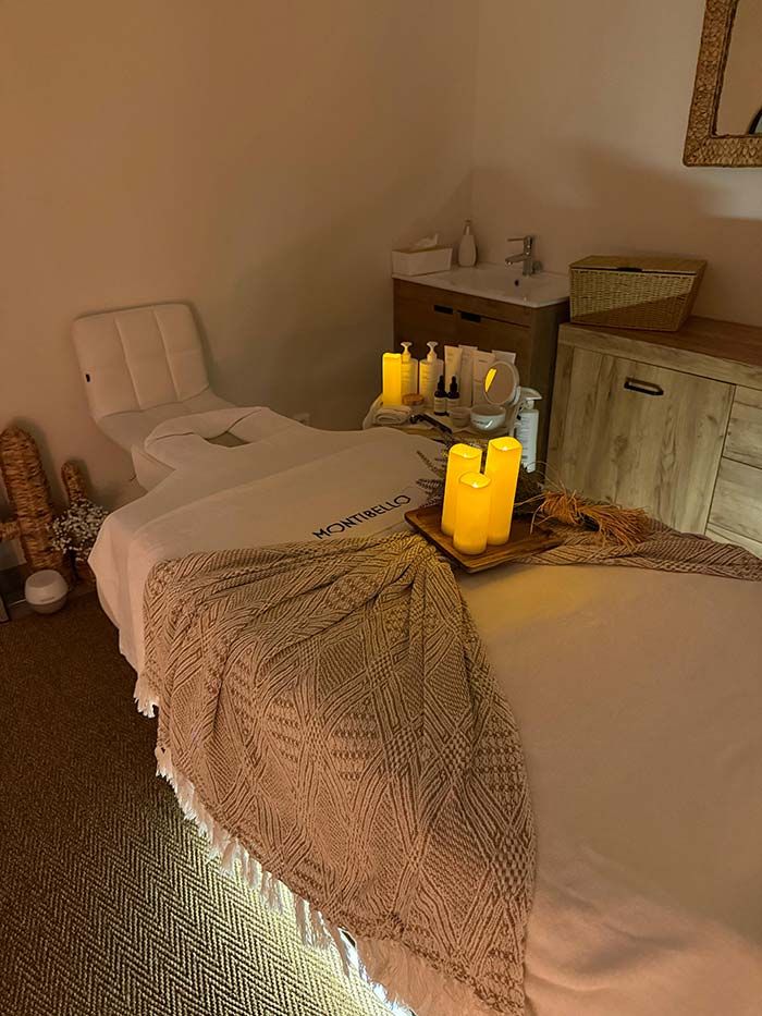 Camilla de masaje en una habitación con luz tenue, velas y productos de spa.