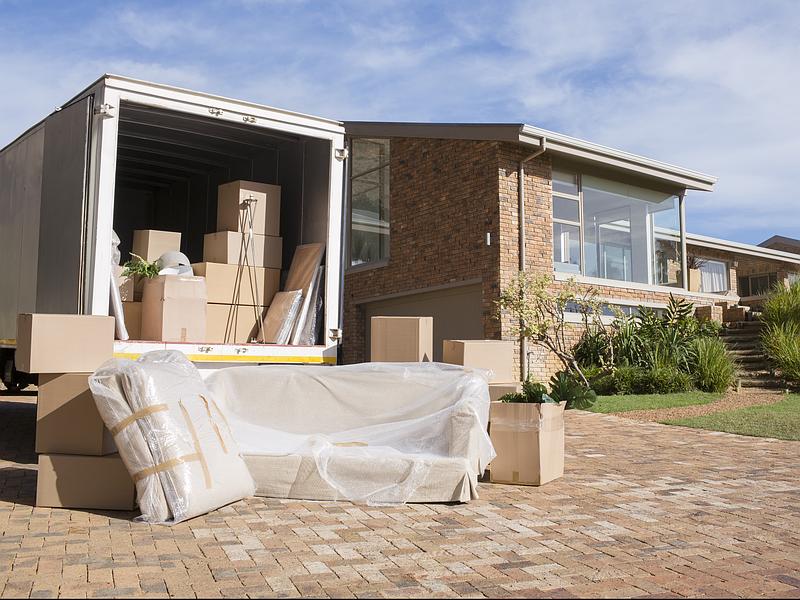 Camion de démangement avec des meubles emballés devant une maison