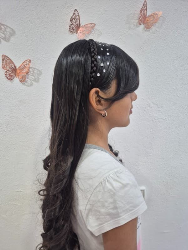 Una niña que lleva una diadema con mariposas en la pared detrás de ella.