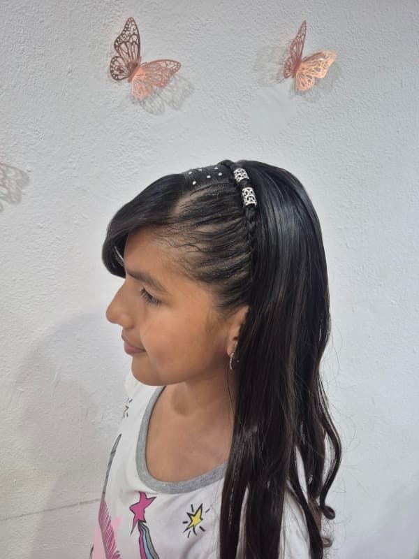 Una niña que lleva una diadema con mariposas en la pared detrás de ella.