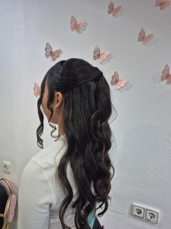 Una mujer con cabello largo está parada frente a una pared con mariposas en ella.