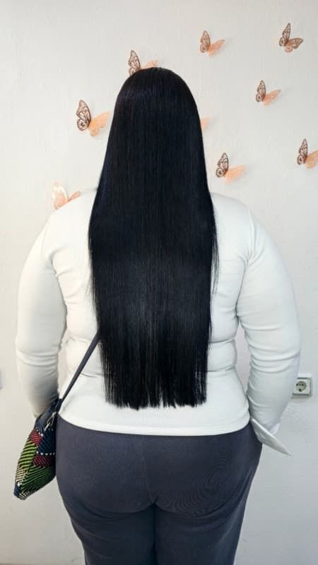 Una mujer con cabello largo y negro está parada frente a una pared con mariposas en ella.