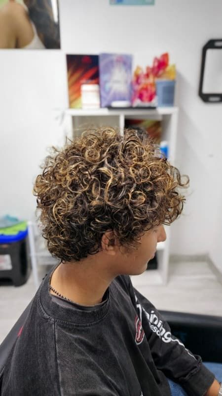 Un hombre con cabello rizado está sentado en una silla en un salón.