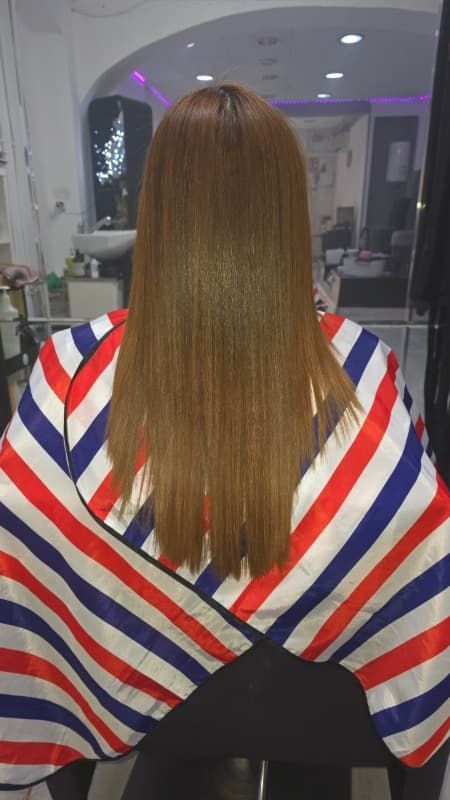 Una mujer está sentada en una silla vistiendo una capa de rayas rojas, blancas y azules.