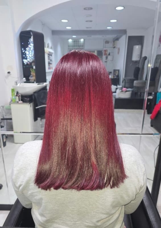 Una mujer con cabello rojo está sentada en una silla en un salón.