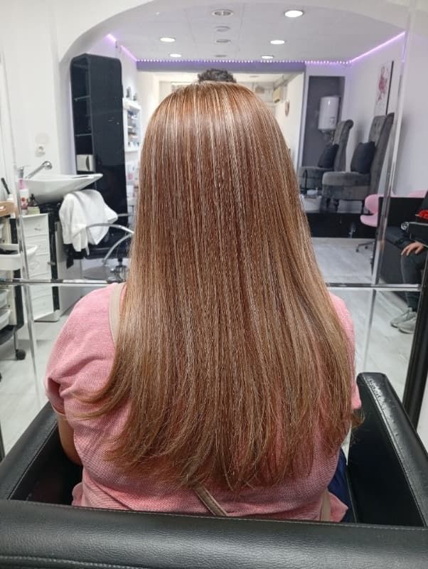 Una mujer con cabello largo está sentada en una silla en un salón.