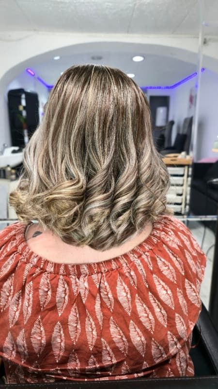 Una mujer está sentada en una silla con su cabello en un salón.