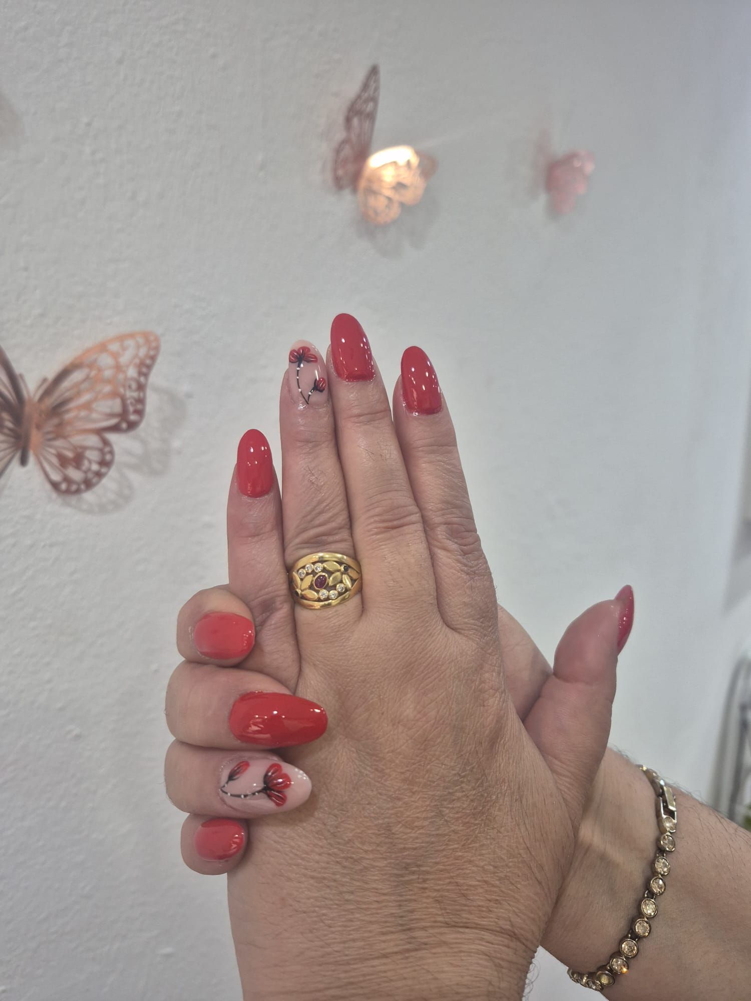La mano de una mujer con uñas rojas y un anillo de oro.