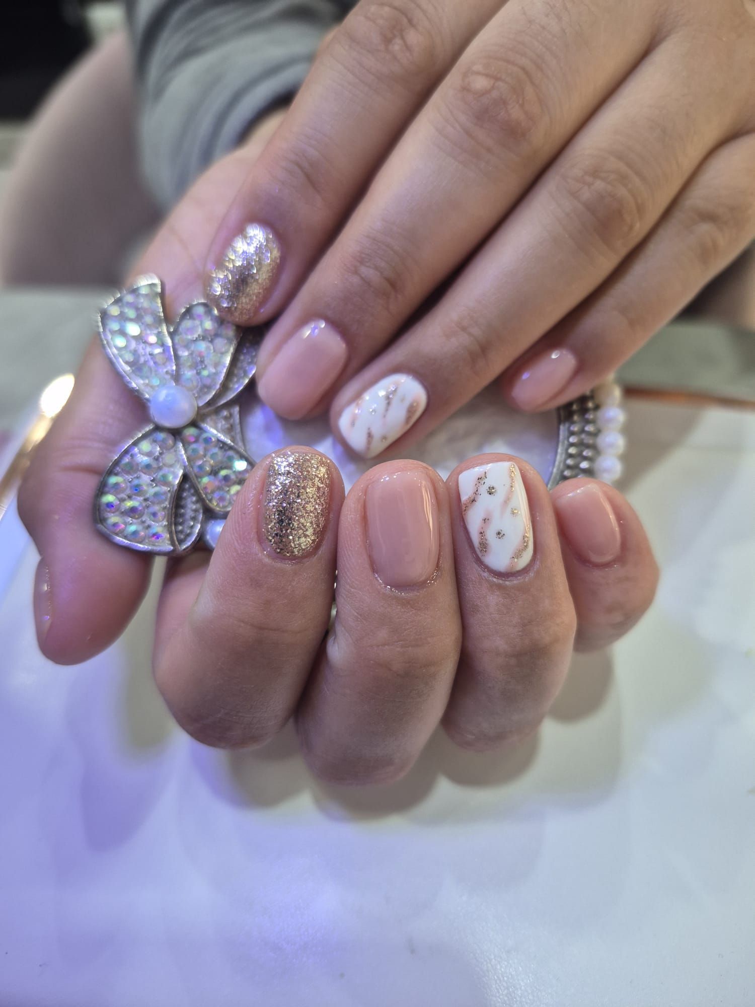 Un primer plano de las uñas de una mujer con una flor en el dedo.