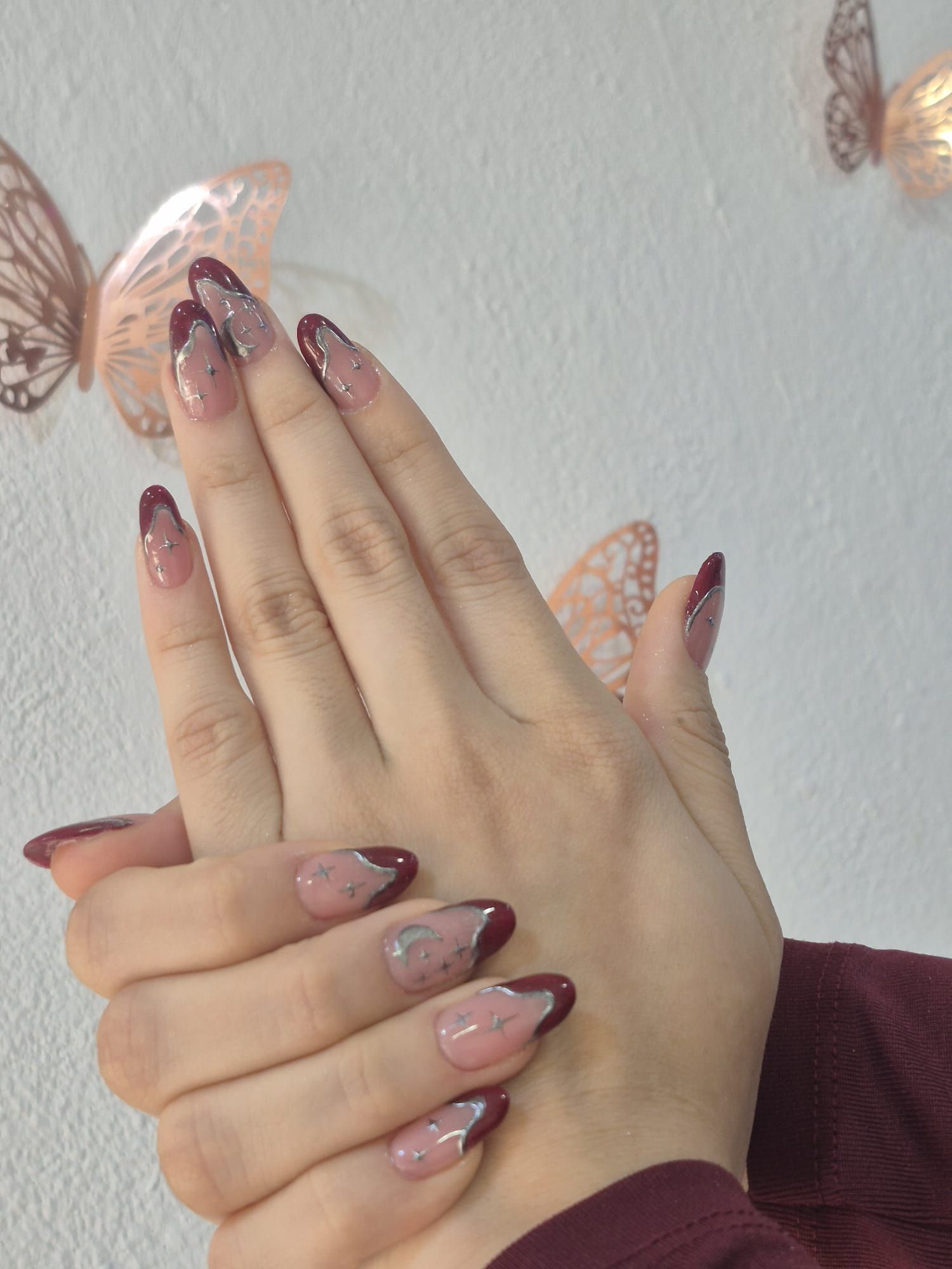 Un primer plano de las uñas de una persona con mariposas en el fondo.