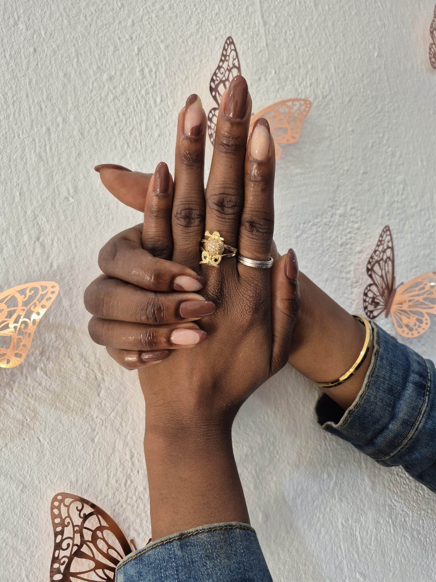 Las manos de una mujer están apiladas una encima de otra con mariposas en el fondo.