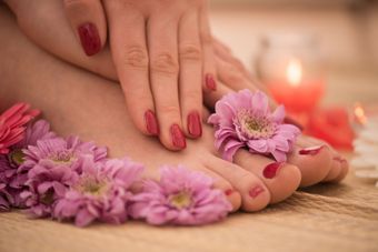 Un primer plano de los pies de una mujer con flores y una vela.