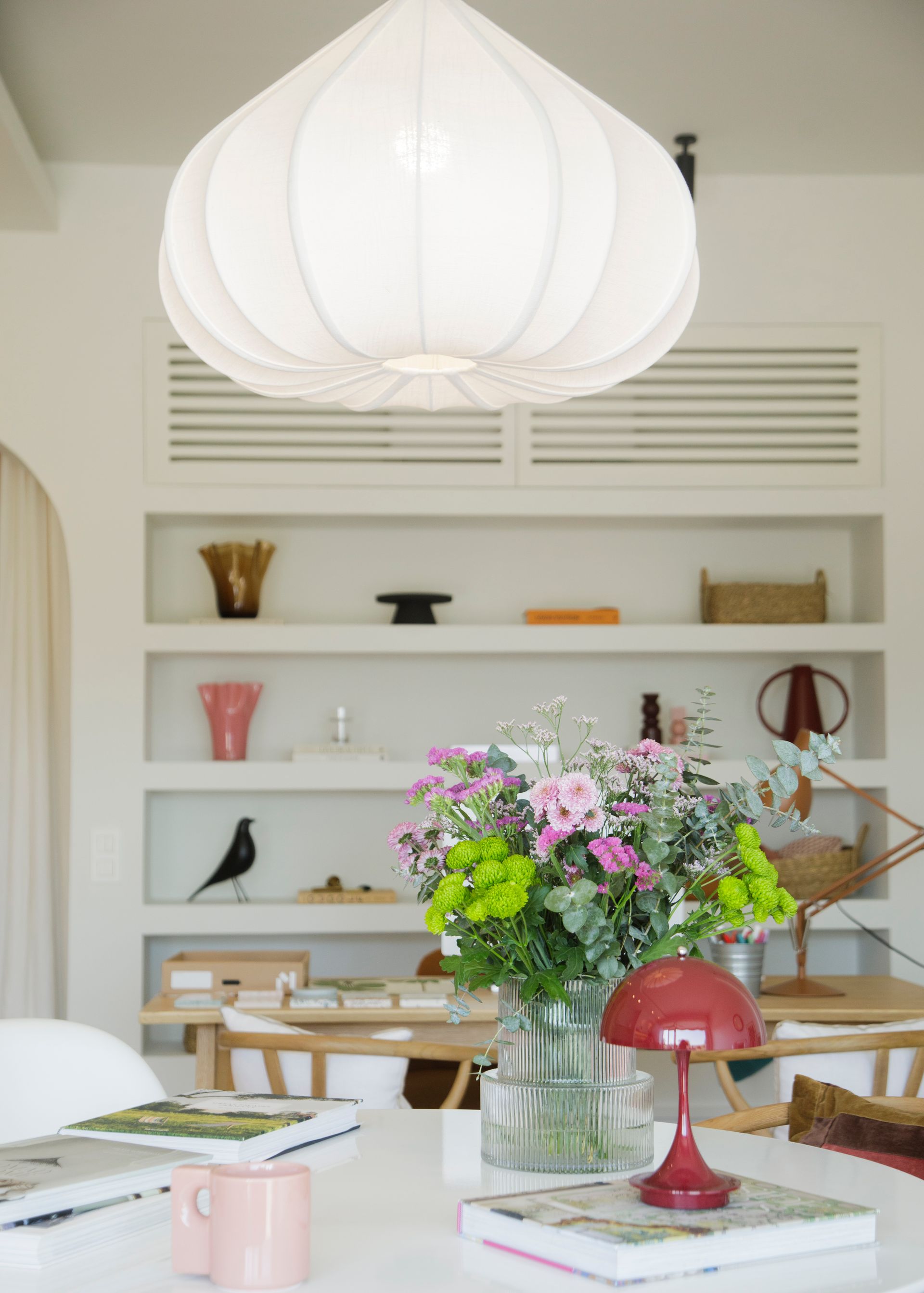 Interior de un restaurante moderno con barra, mesas, plantas y grandes lámparas de globo.