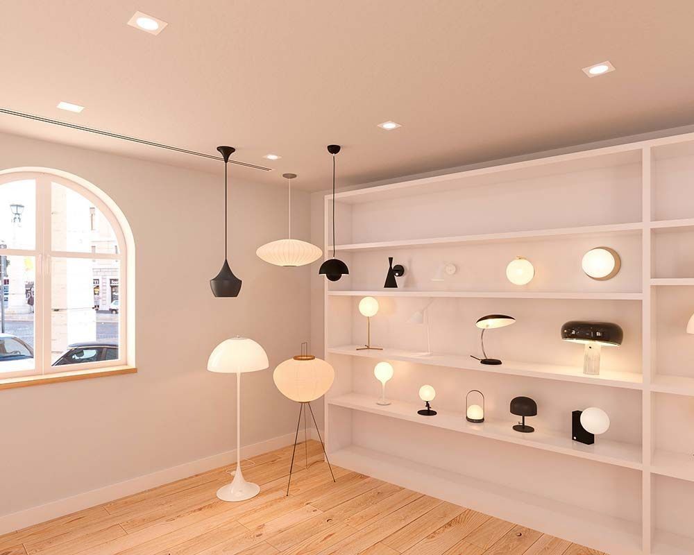 Un interior bien iluminado con varias lámparas en los estantes y el suelo. A la izquierda hay una gran ventana.