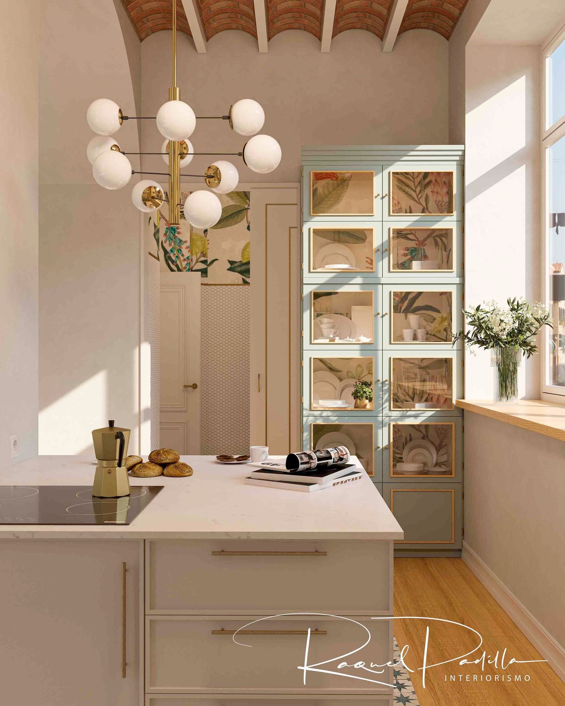 Cocina con un armario azul claro, una isla blanca y una lámpara de araña dorada. La luz del sol entra a raudales por una ventana.