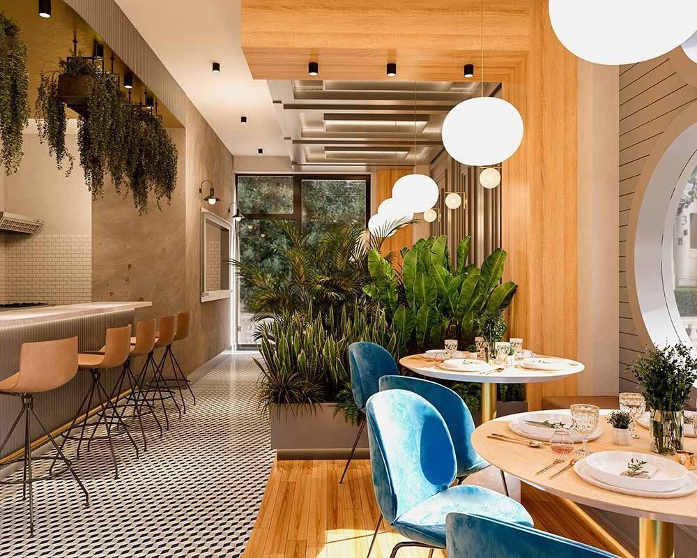 Interior de un restaurante moderno con mesas, sillas y barra. Las plantas y la luz natural crean un ambiente cálido.