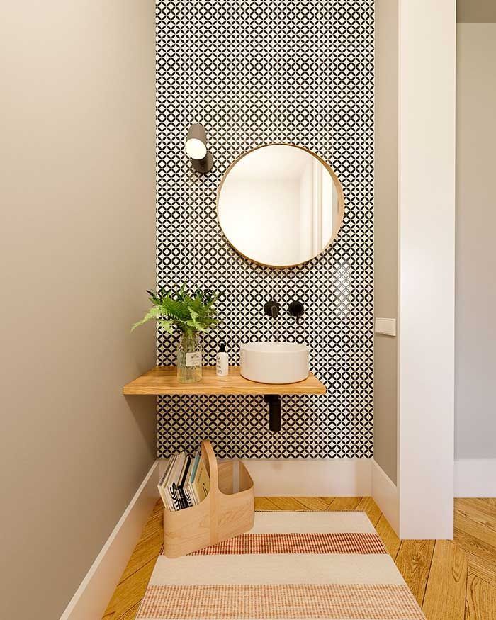 Pequeño tocador con pared decorativa de azulejos estampados, estante flotante de madera con lavabo y espejo redondo.