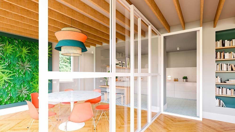Comedor moderno con mampara de cristal. Sillas naranjas rodean una mesa redonda blanca. Pared verde con plantas, techo de madera y librería.