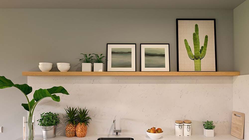 Estante de cocina con decoración: estampado de cactus, plantas pequeñas, cuencos y obras de arte enmarcadas.