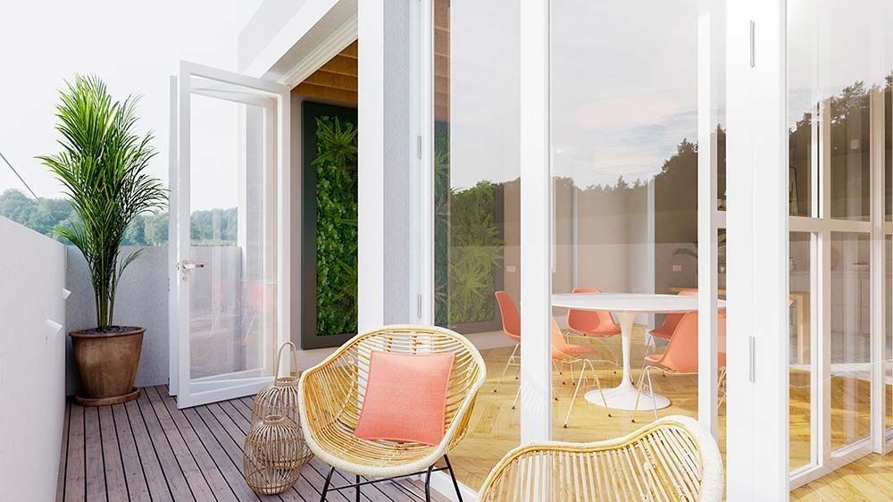 Balcón con sillas de ratán, planta en maceta y una vista a través de puertas de vidrio abiertas a una mesa y sillas naranjas.