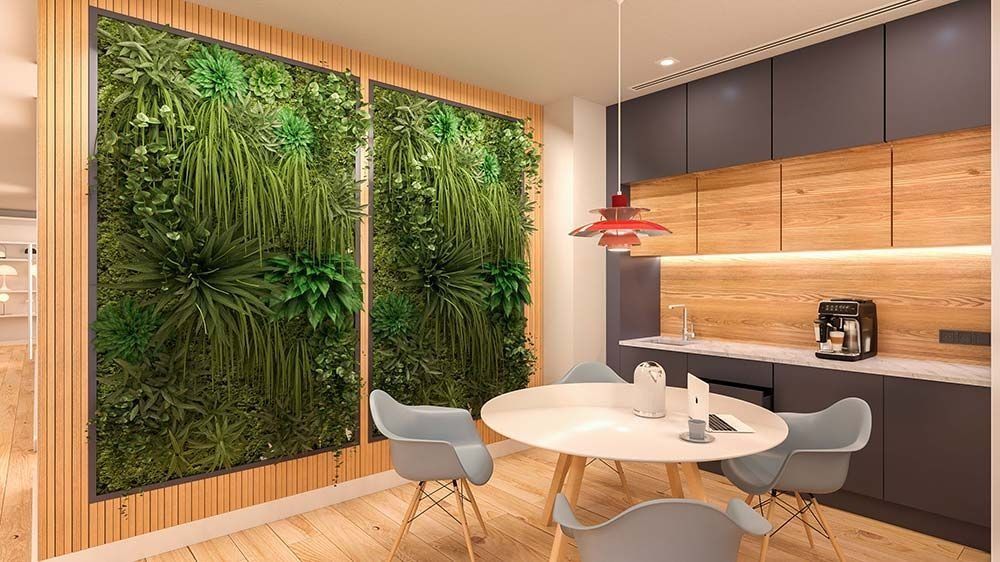 Comedor con pared verde, mesa redonda y cocina moderna.