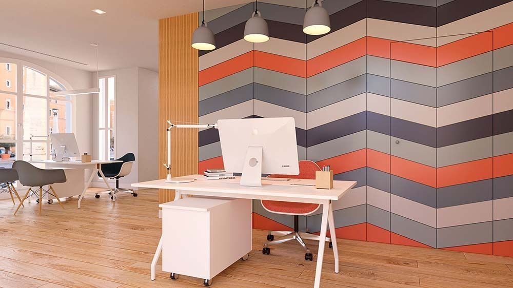 Espacio de oficina moderno con pared con acento en forma de chevron, escritorios e iluminación superior.