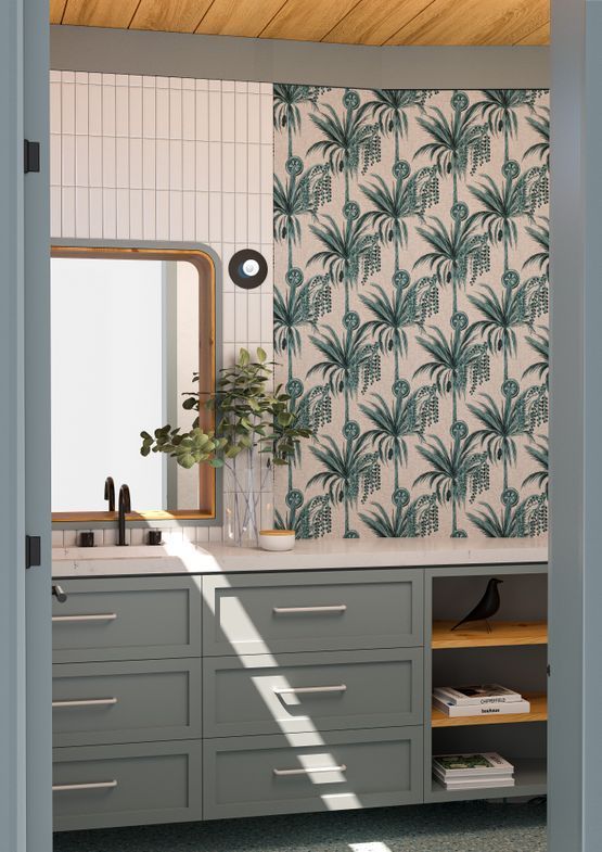 Baño con muebles verdes, papel tapiz de palmeras, espejo y un interior iluminado por el sol.