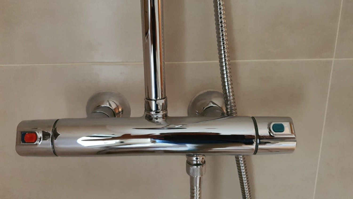 Pared de ladrillos a la vista con tuberías azules y rojas y un sistema de drenaje negro.