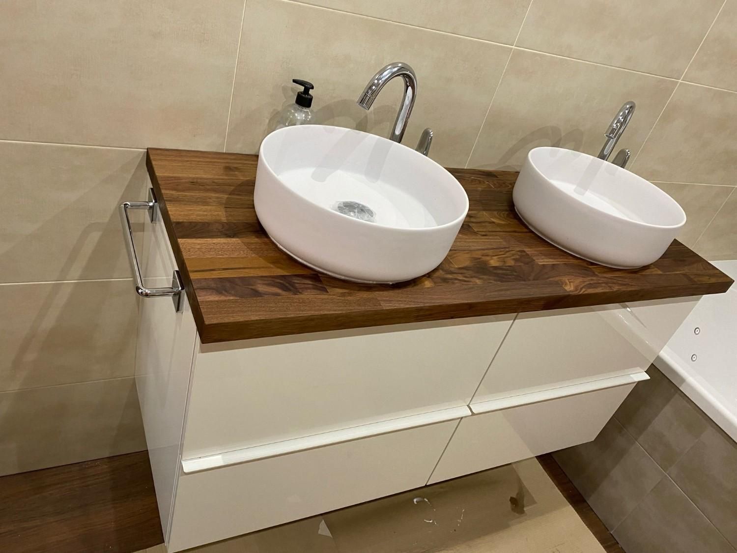 Mueble de baño blanco y marrón con lavabos de dos senos, grifería cromada y cajones de color blanco brillante.