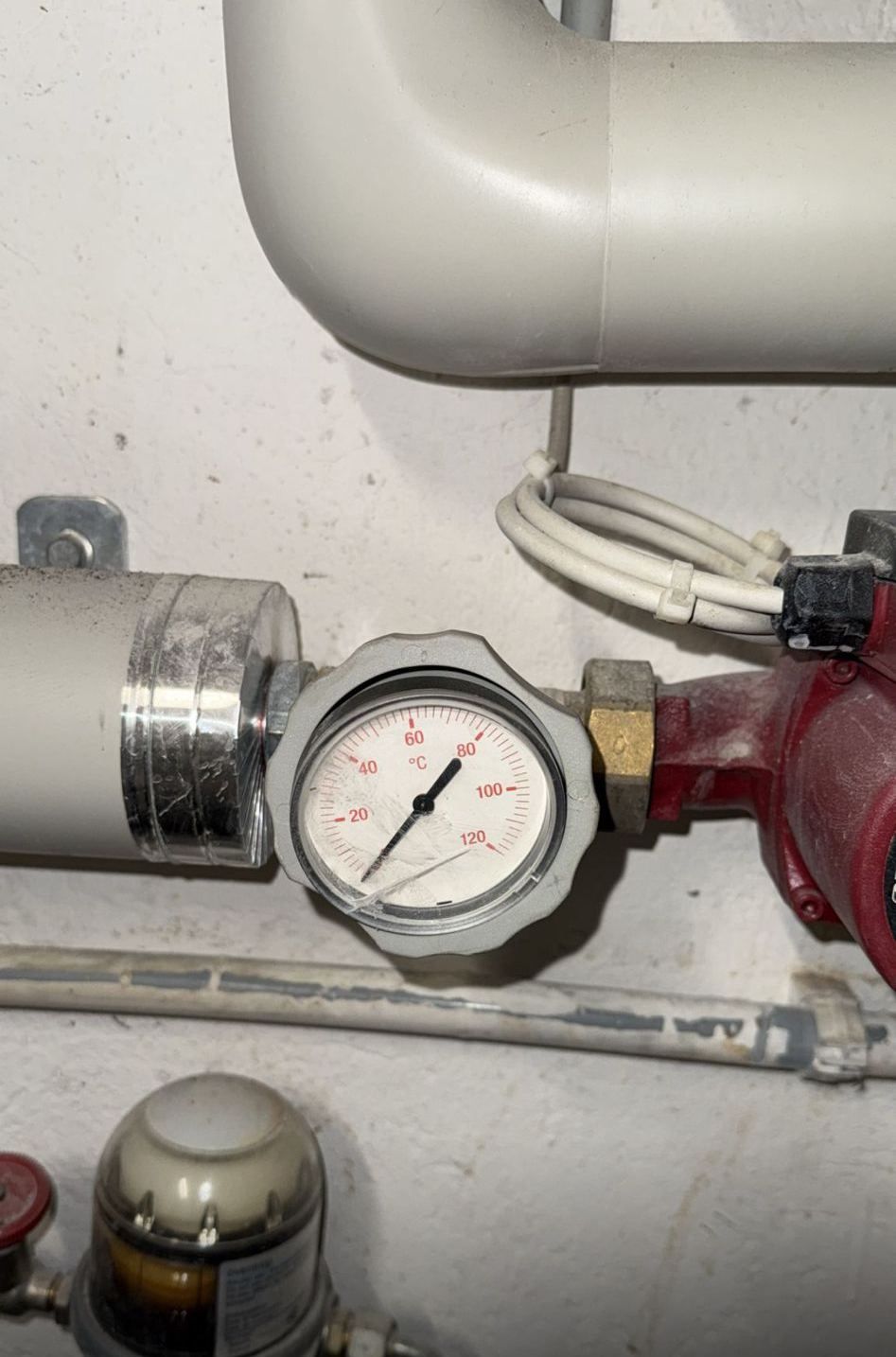 Manometer an einem Rohr mit einer Anzeige von 3 bar, mit zugehörigen Sanitärkomponenten.