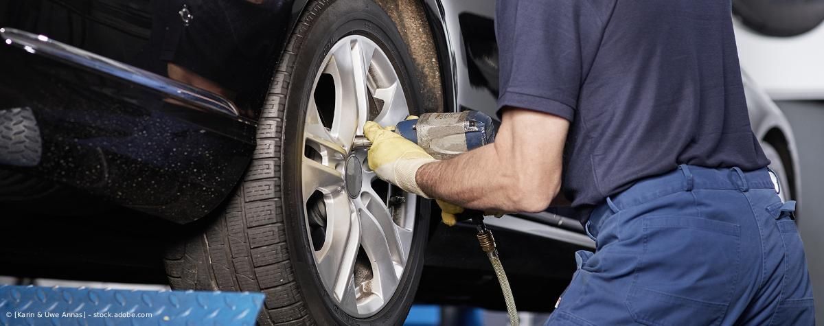 Ein Mechaniker poliert in einer Werkstatt mit einer Poliermaschine eine Autofelge.