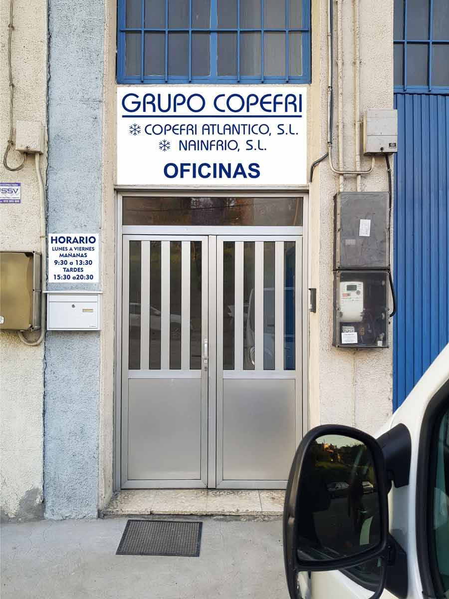 Un coche blanco está aparcado delante de una puerta que dice grupo copefri oficinas