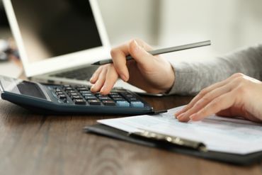 Person prüft Untelragen mit Taschenrechner