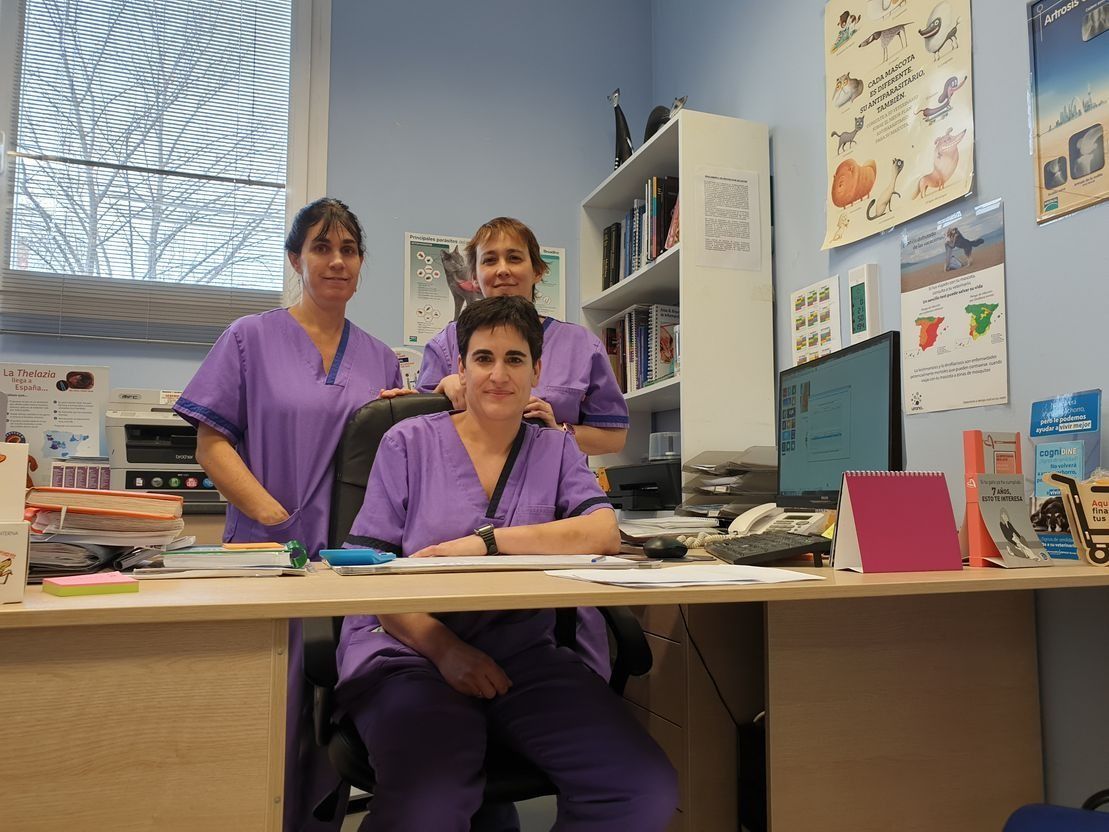 Tres mujeres con uniformes morados posan para una fotografía delante de un escritorio.