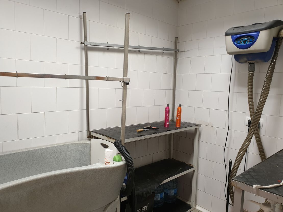 Una habitación con bañera, estantes y una aspiradora.