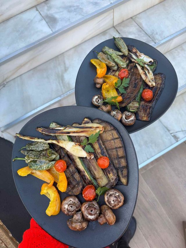 Se muestran dos platos negros de verduras a la parrilla.