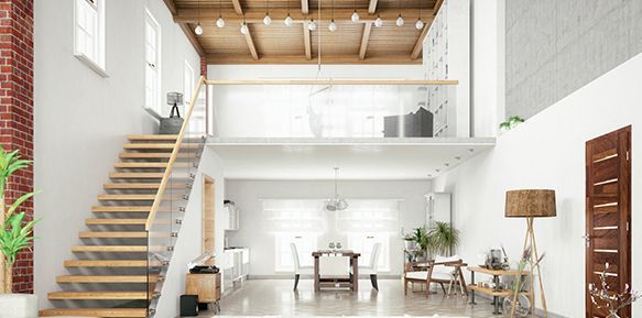 Un loft moderne avec un escalier en bois, de hauts plafonds et un balcon au deuxième étage donnant sur une salle à manger.