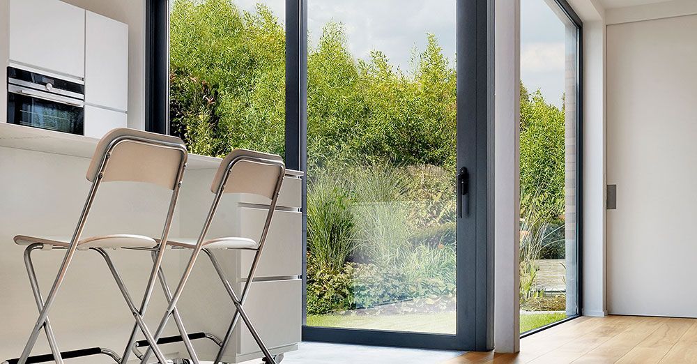 Deux chaises pliantes sont placées devant une grande fenêtre avec vue sur la verdure.