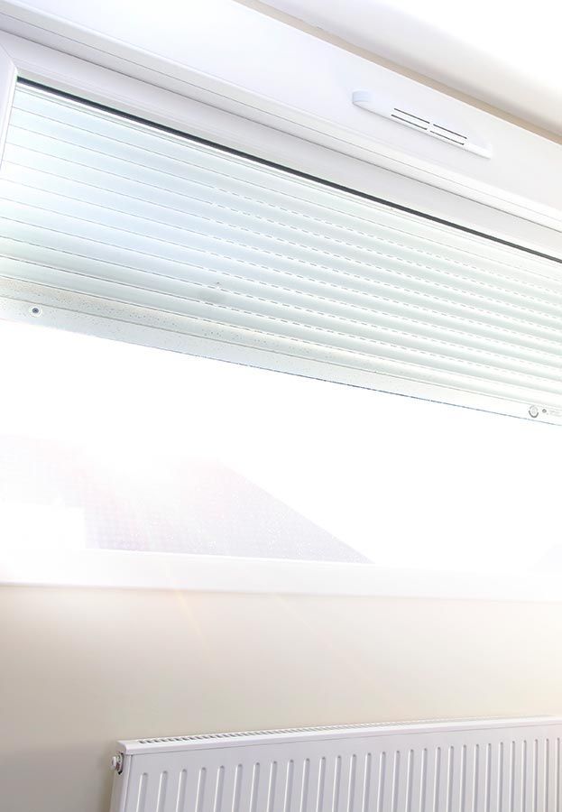 Fenêtre blanche avec stores texturés fermés au-dessus d'un radiateur.