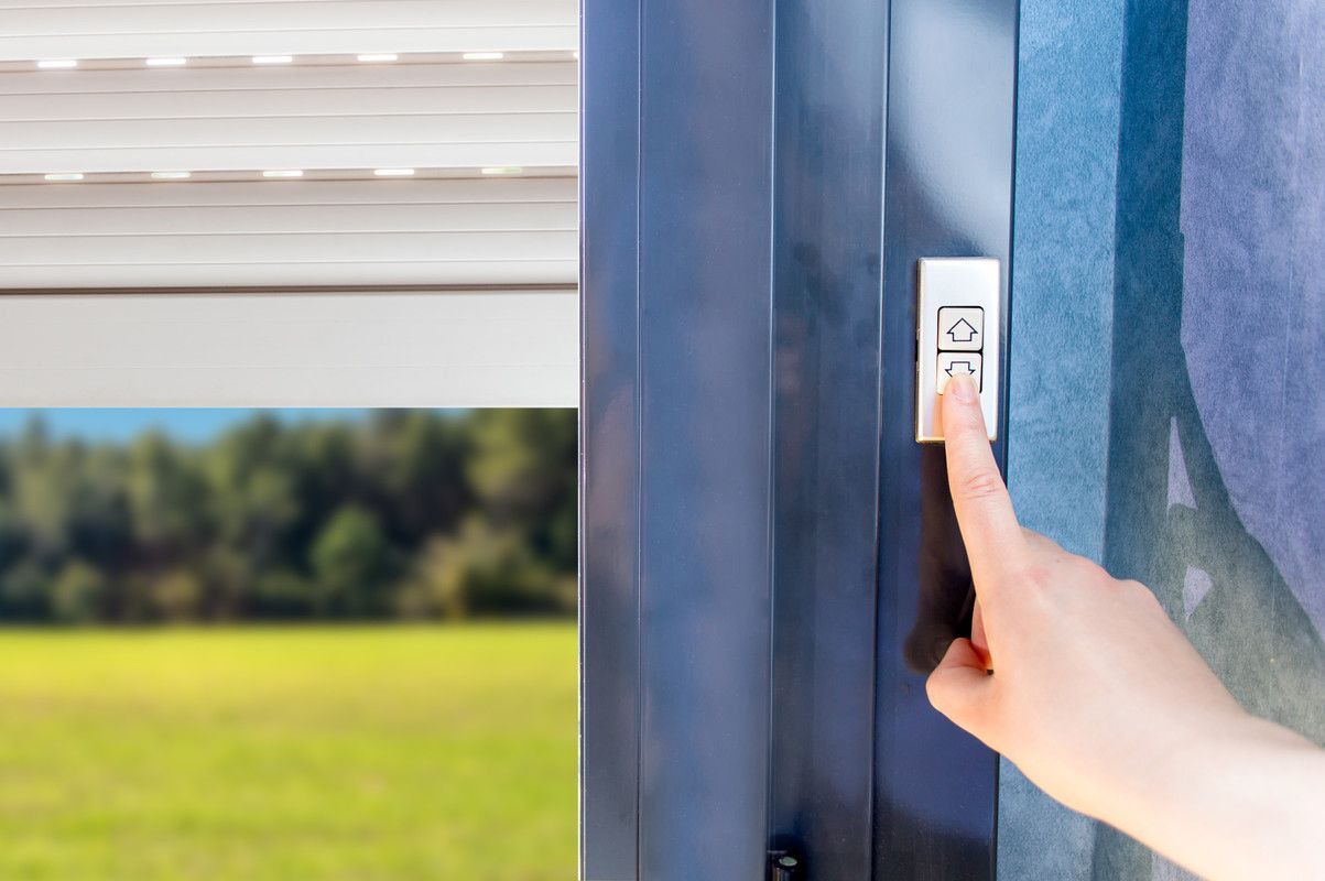 La main appuie sur un bouton pour contrôler un store de fenêtre extérieur.