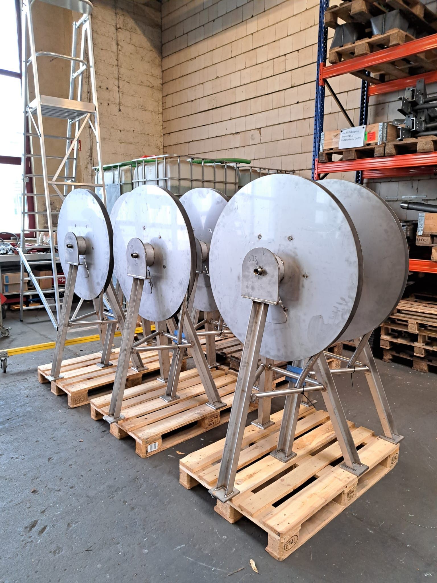 In einem Lagerhaus steht eine Reihe Edelstahlflaschen auf Holzpaletten.