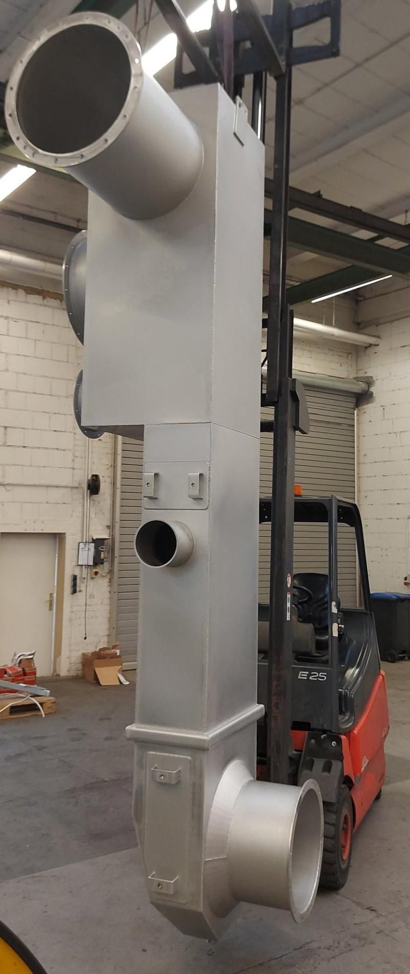 In einem Lagerhaus wird ein großes Metallrohr von einem Gabelstapler angehoben.