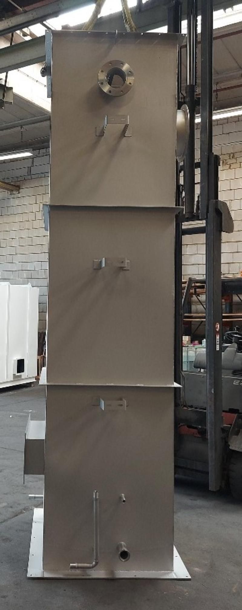 In einem Lagerhaus steht neben einem Gabelstapler ein großer Edelstahltank.